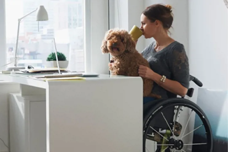 Woman in wheelchair with dog at desk